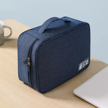 Pochette organisateur compacte de couleur bleue, posée sur un bureau avec une tasse et un ordinateur portable, idéale pour le rangement des accessoires électroniques et cosmétiques.